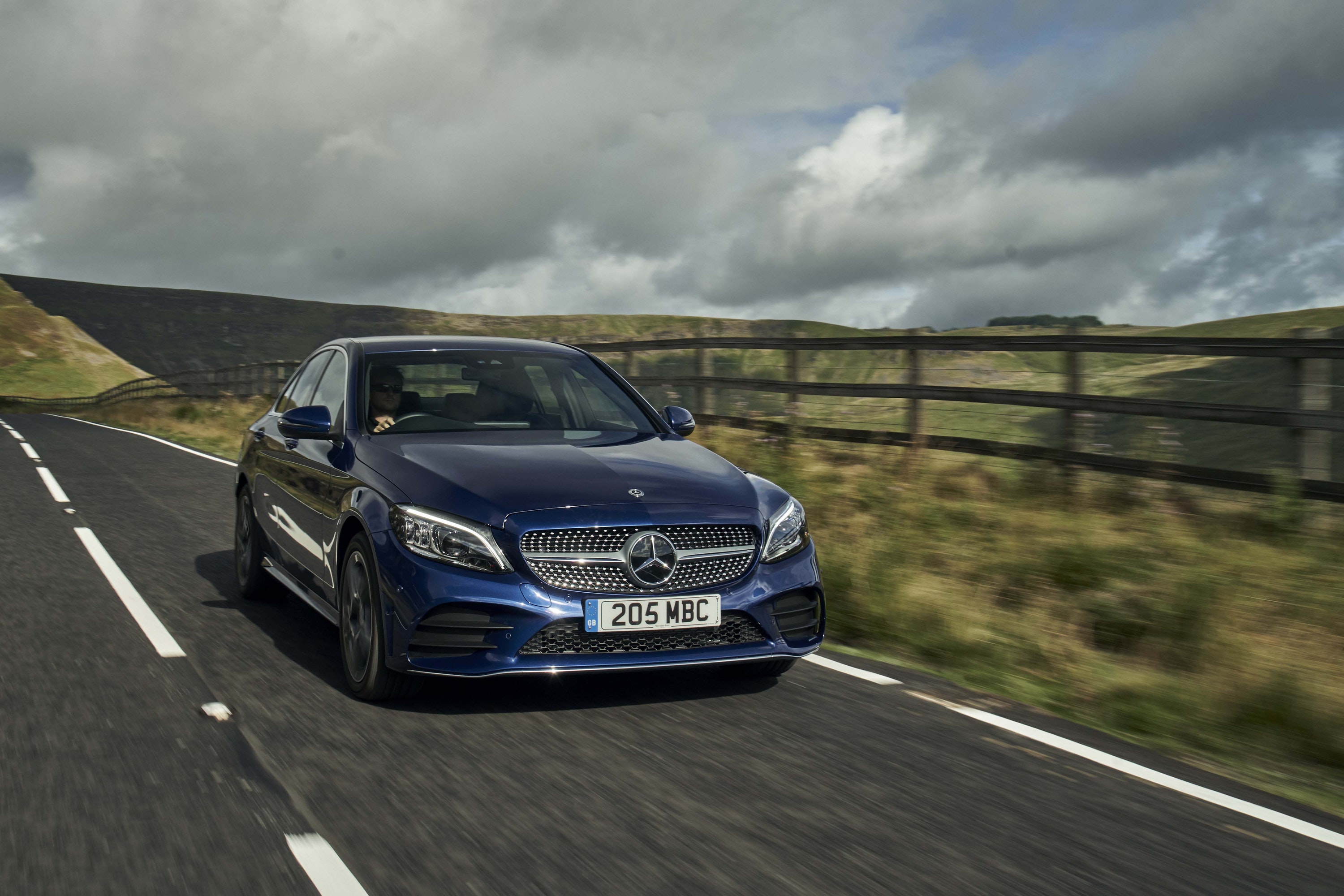 Front view of blue Mercedes C-Class driving on a road